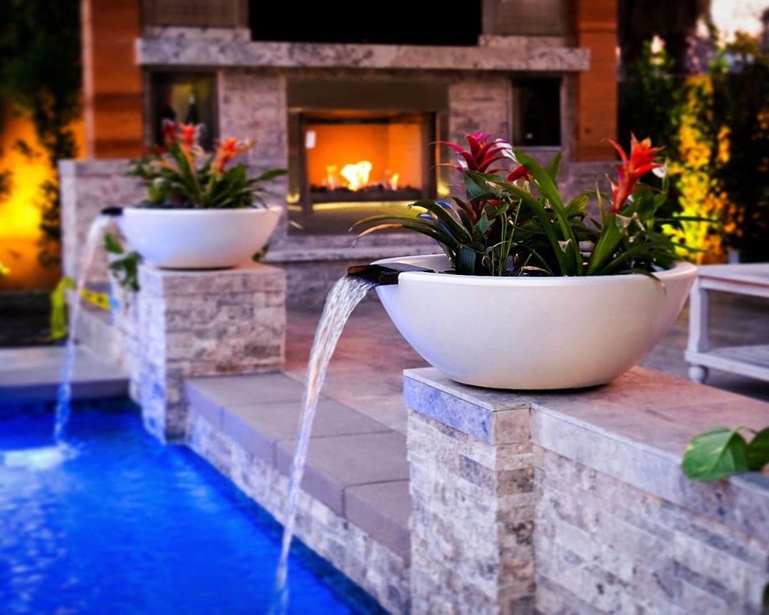 Two white Sedona planter and water bowls on stone pillars pouring into a pool