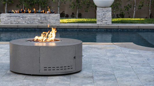 Isla 60 inch round fire pit in Silver Vein powder coat beside a pool, The Outdoor Plus (color rendering from the official finish)