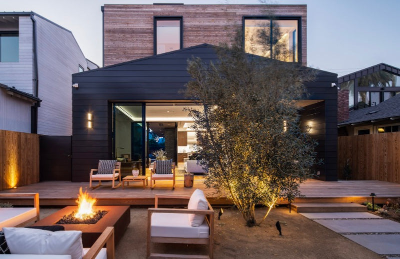Rectangular gas fire pit on the deck of a modern home at dusk