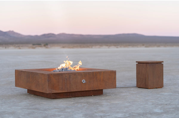 Corten steel square gas fire pit on a desert lake bed at sunset