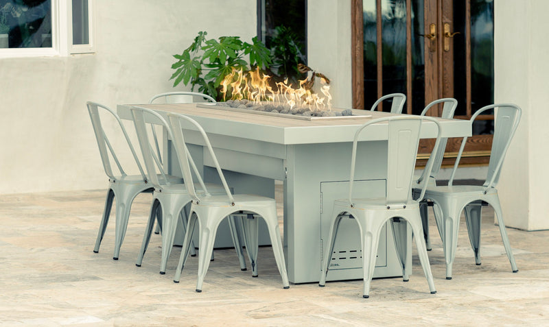 Gas fire dining table with a linear burner and metal chairs on a patio