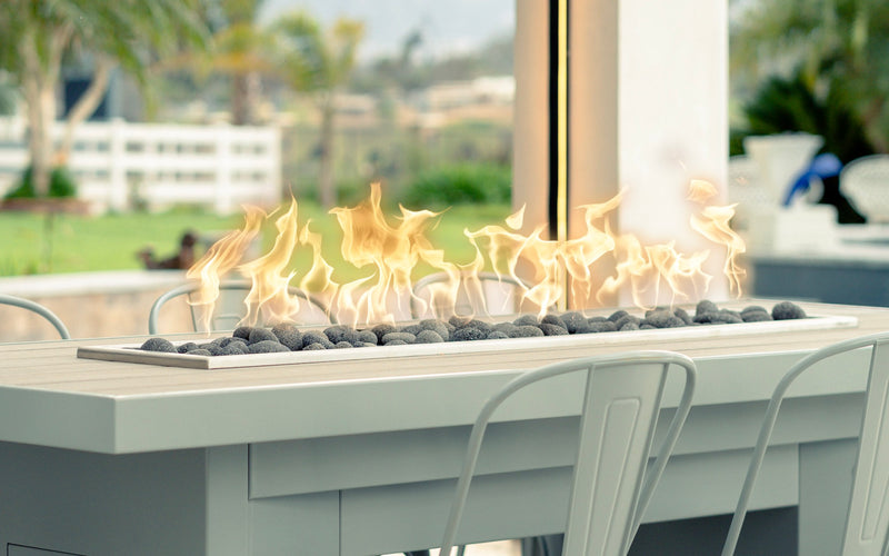 Close-up of a linear gas burner with lava stones in a fire dining table