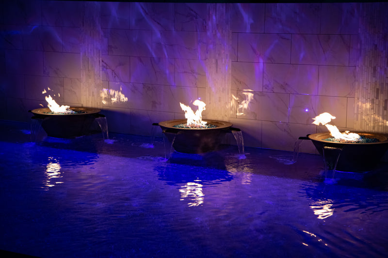 Three fire and water bowls pouring into a pool at night with blue lighting